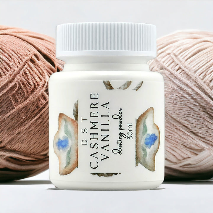 30ml bottle of Cashmere Vanilla scent body powder against a white background with 2 balls of cream colored yarn.