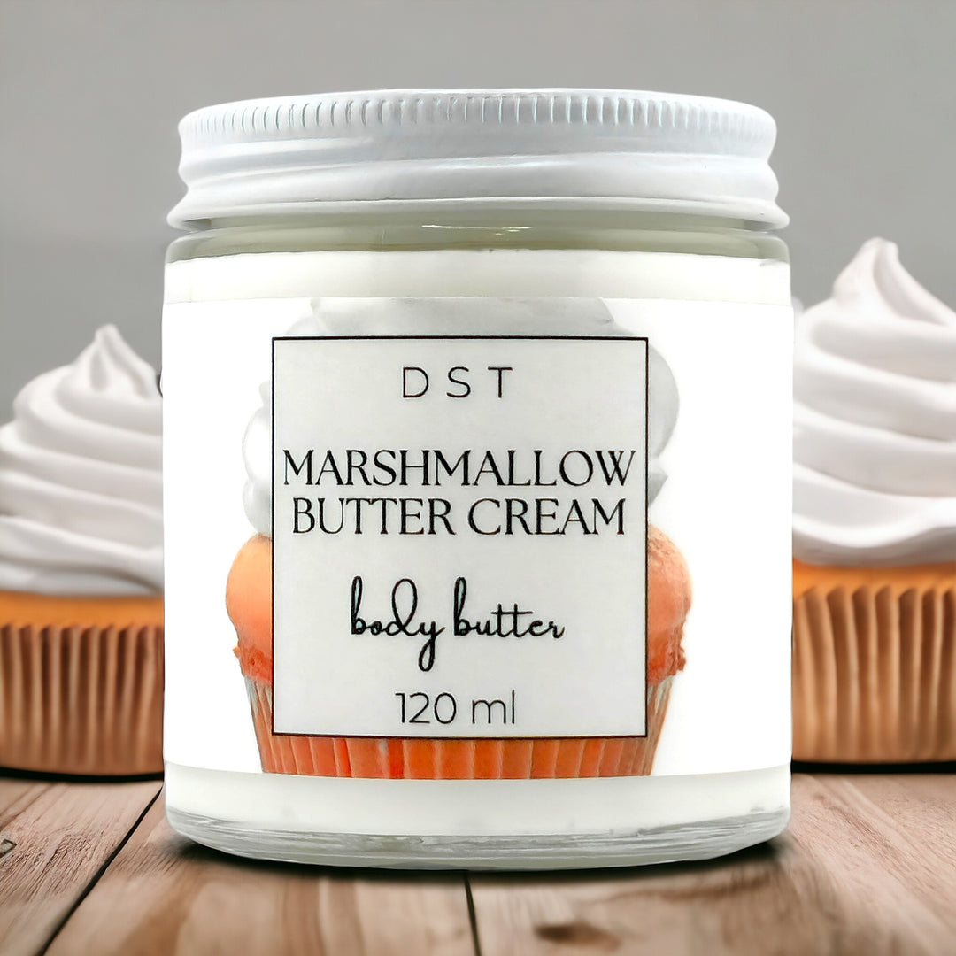 120ml jar of Marshmallow Butter Cream scented body butter sitting on a wood countertop with 2 vanilla cupcakes in the background. 