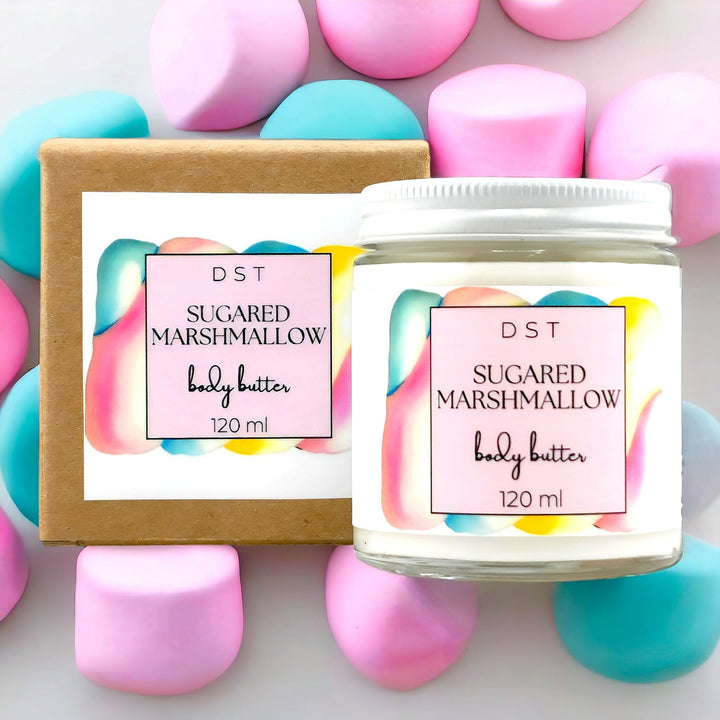 120ml jar of Sugared Marshmallow scented body butter and the box it is packaged in against a light purple background with pastel colored Marshmallows. 