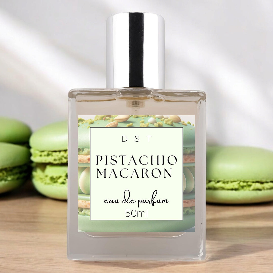 50ml bottle of Pistachio Macaroon Eau de Parfum sitting on wood counter top with white background and green macarons surrounding the bottle.