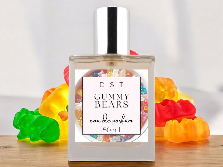 50ml bottle of Gummy bears parfum sitting on a wood counter top with bright colored Gummy bears behind it on a white shadowy background.