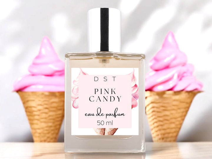 50ml bottle of Pink Candy Eau de parfum sitting on wood countertop with 2 waffle cones filled with bright pink ice cream in the white background.