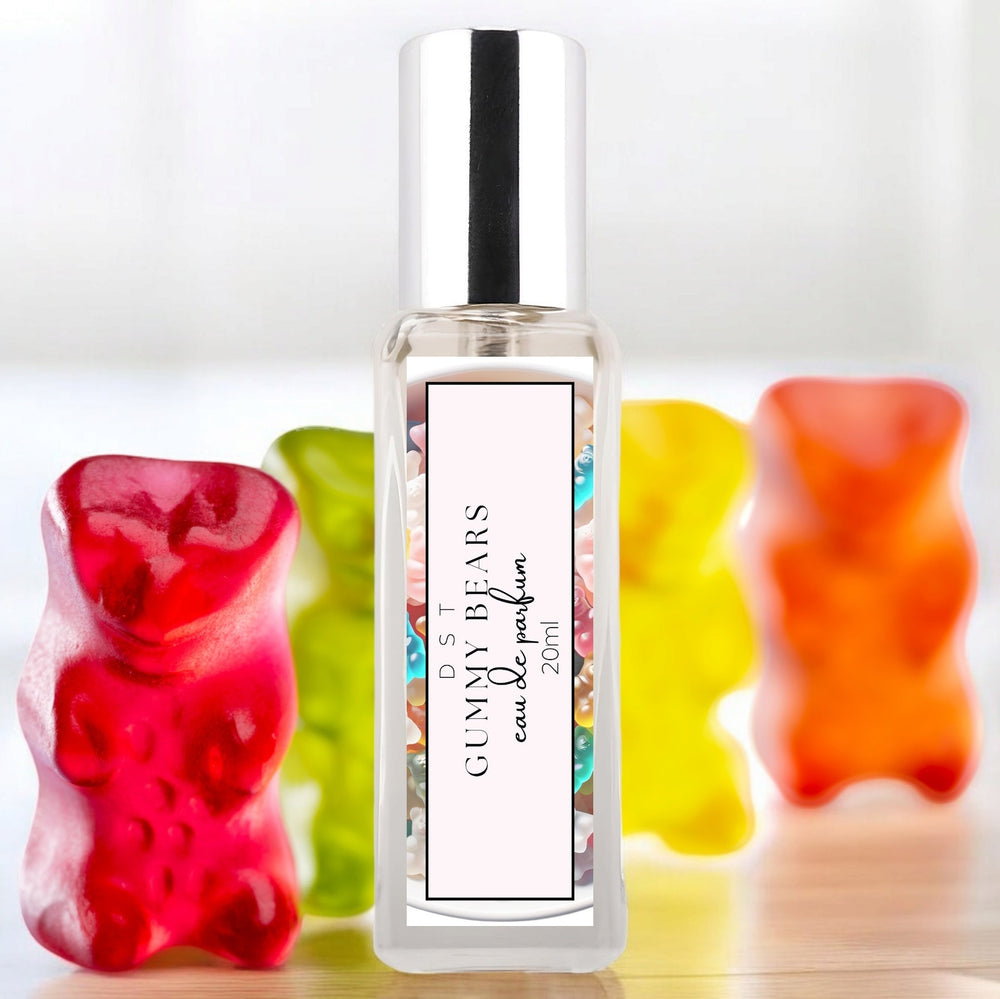 20ml bottle of Gummy bears parfum sitting on a wood counter top with bright colored Gummy bears behind it on a white shadowy background.