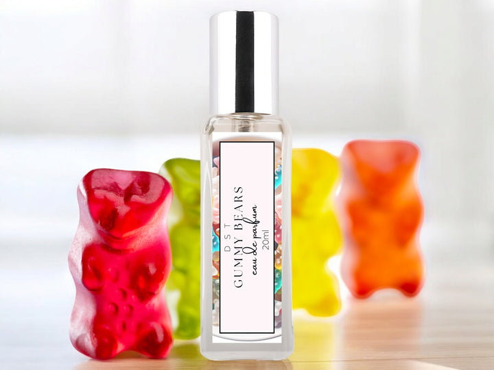 20ml bottle of Gummy bears parfum sitting on a wood counter top with bright colored Gummy bears behind it on a white shadowy background.