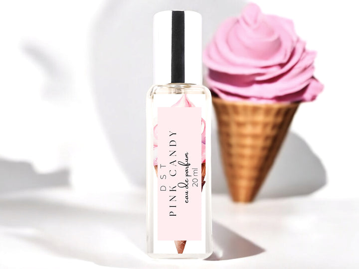 20ml bottle of Pink Candy Eau de parfum sitting on wood countertop with a waffle cone filled with bright pink ice cream in the white shadowy background.