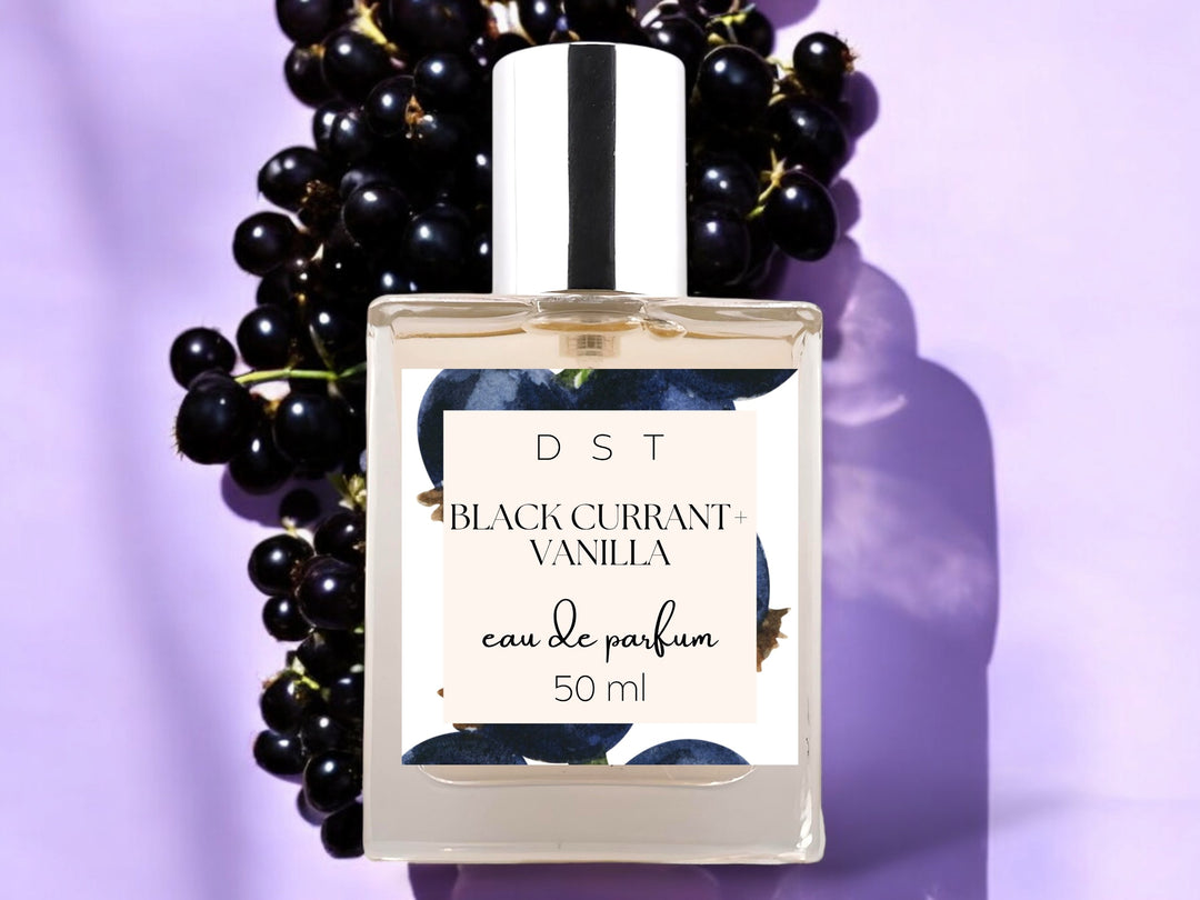 50 ml bottle of black currant vanilla eau de parfum on purple background with black currants