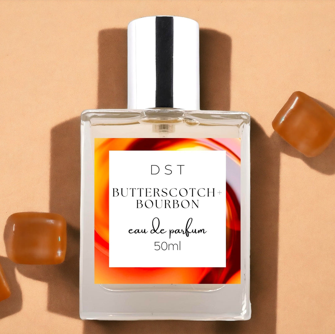 50ml bottle of Butterscotch and Bourbon Eau de Parfum against a tan background with Butterscotch candies. 