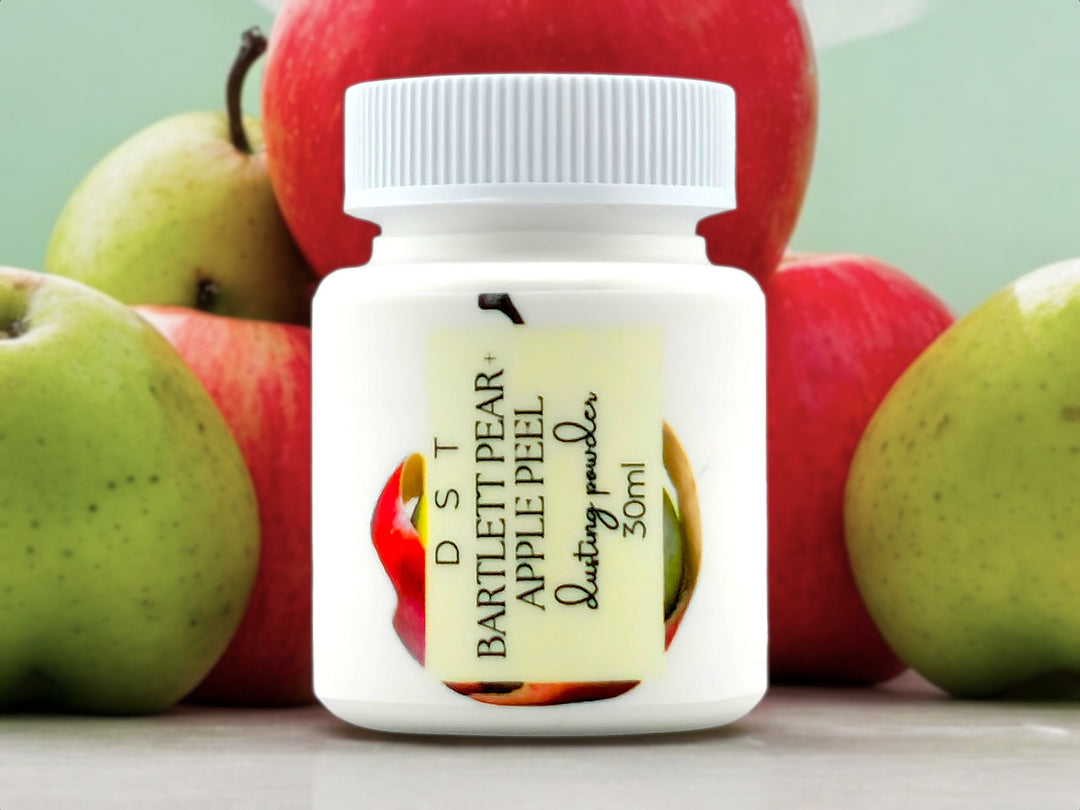 30ml bottle of Bartlet Pear and Apple Peel scented body powder surrounded by light green background and red Apples and green pears. 