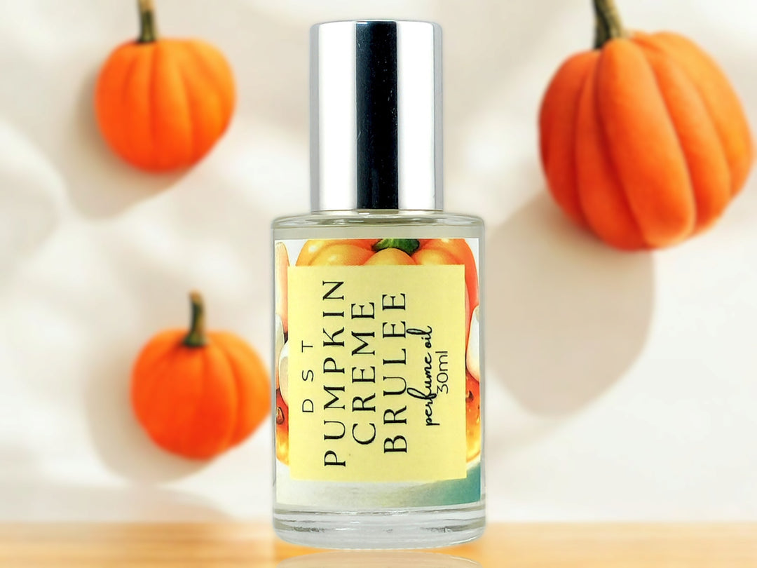 30ml bottle of Pumpkin Creme Brulee perfume oil sitting on wood countertop with 3 fondant pumpkins and cream-colored background.