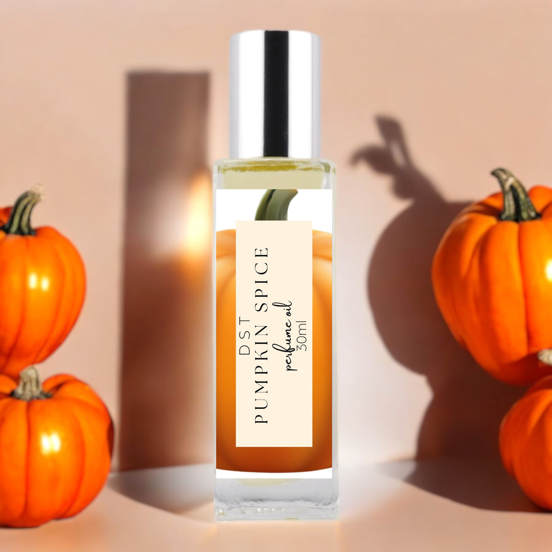 30 milliliter bottle of pumpkin spice perfume oil against a tan background with shiny orange pumpkins.