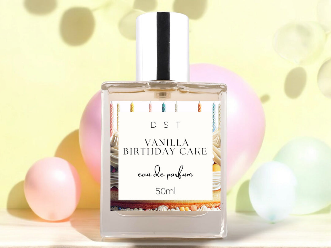 50ml bottle of Vanilla birthday Cake Eau de Parfum spray sitting on a wood countertop with pastel pink and blue balloons against a pastel yellow background.