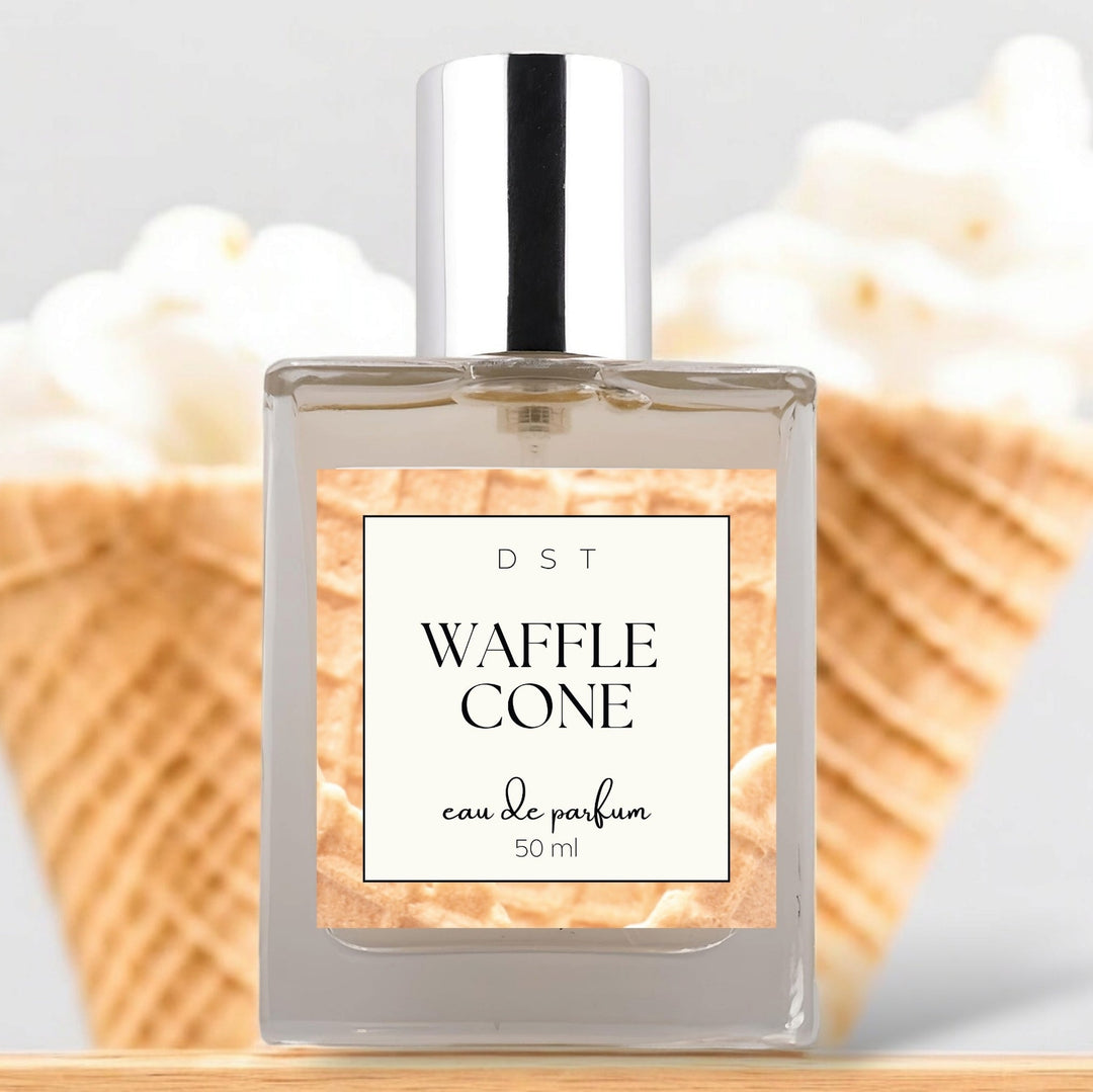 50ml bottle of Waffle Cone Eau de Parfum sitting on wood counter top with 2 Vanilla ice cream cones in the light grey background.