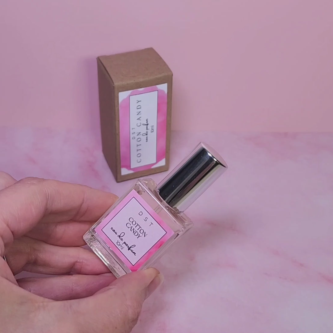 5ml bottle of Cotton Candy Parfum and the box it is packaged in sitting on a pink counter top with pink background. 