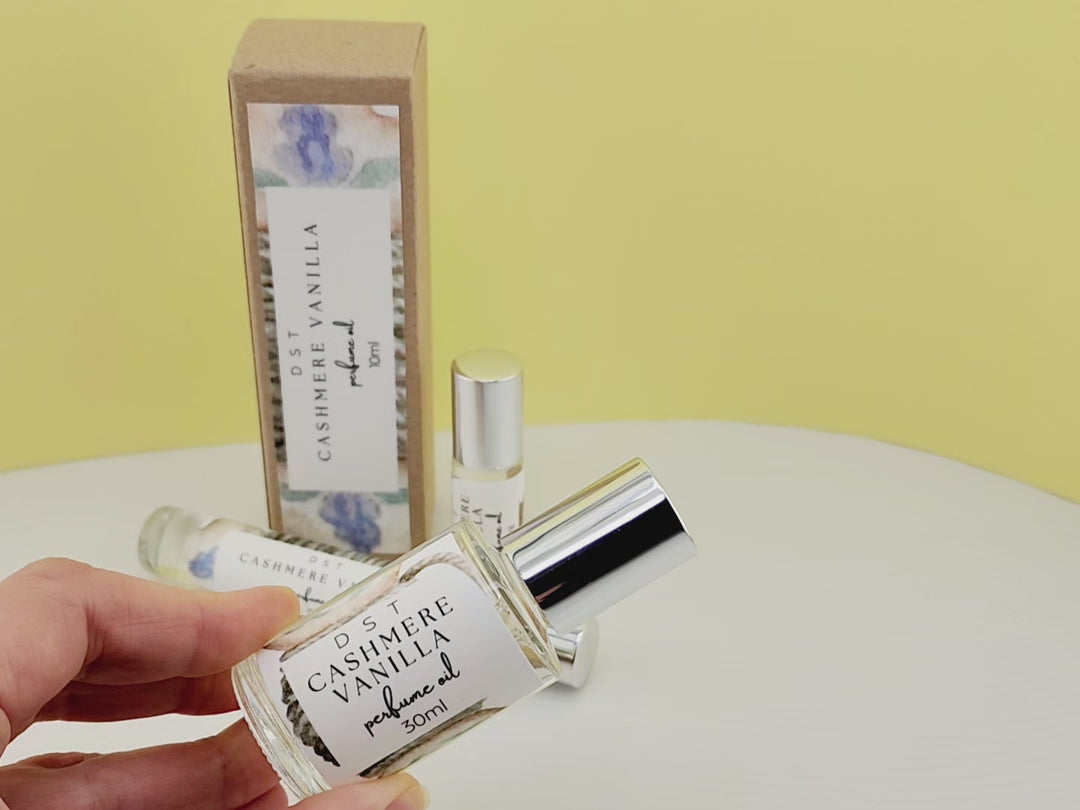 10ml bottle of Cashmere Vanilla perfume oil and the box it is packaged in sitting on white countertop with pale yellow background. 