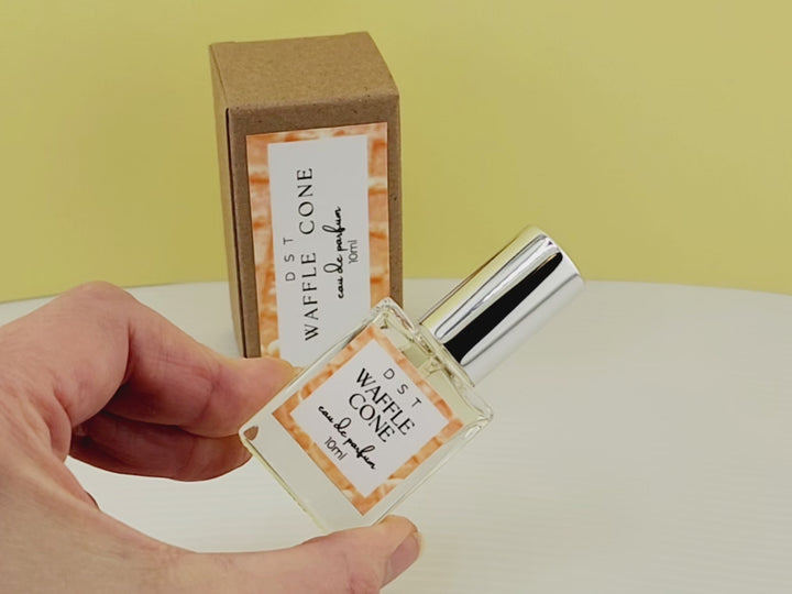 10ml bottle of Waffle Cone Eau de Parfum Spray and the box it is packaged in sitting on a white countertop with Light yellow background. 