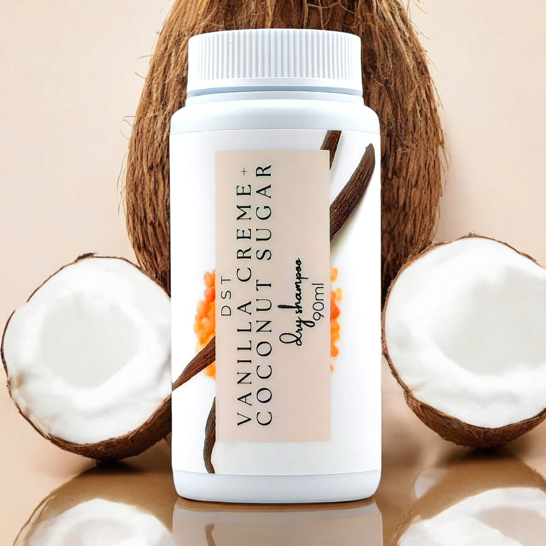 90ml bottle of Vanilla Creme and Coconut Sugar scented Dry Shampoo powder against a tan background with coconuts. 